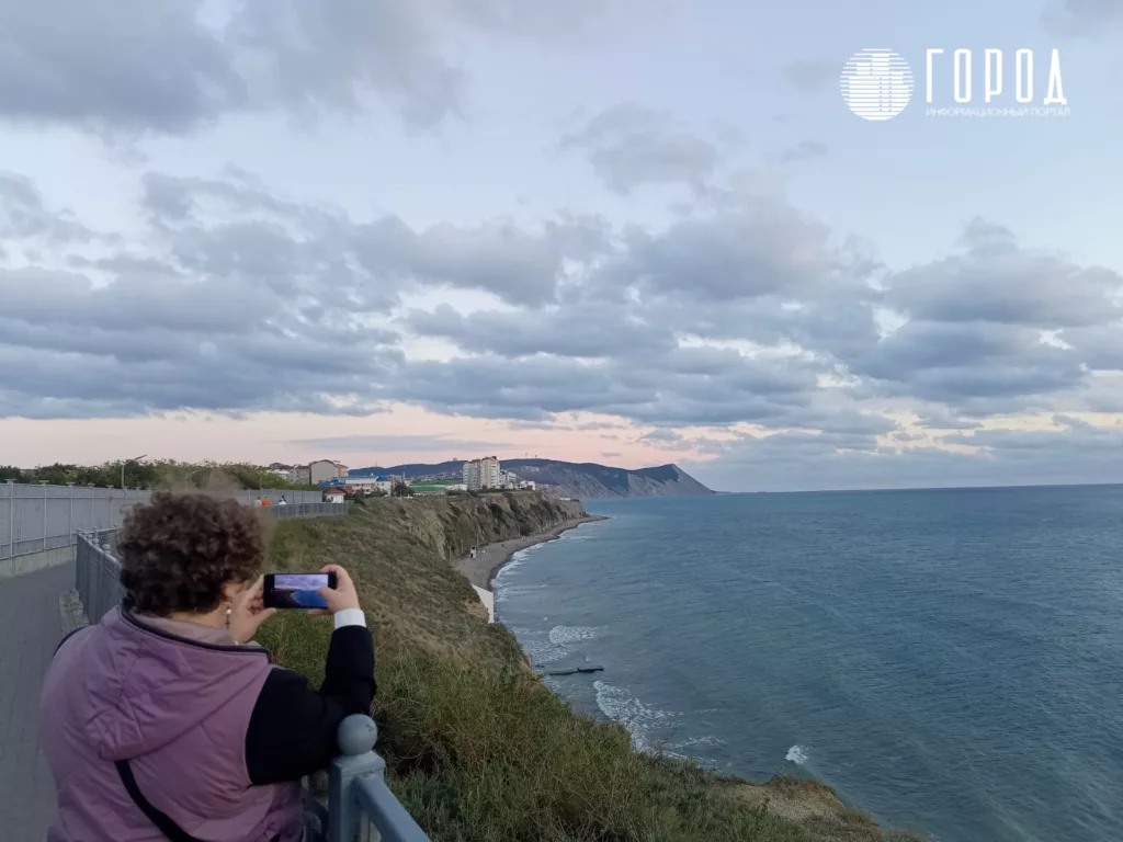 Туристы становятся редкими гостями на побережье. Женщина фотографирует высокий берег в Анапе. 