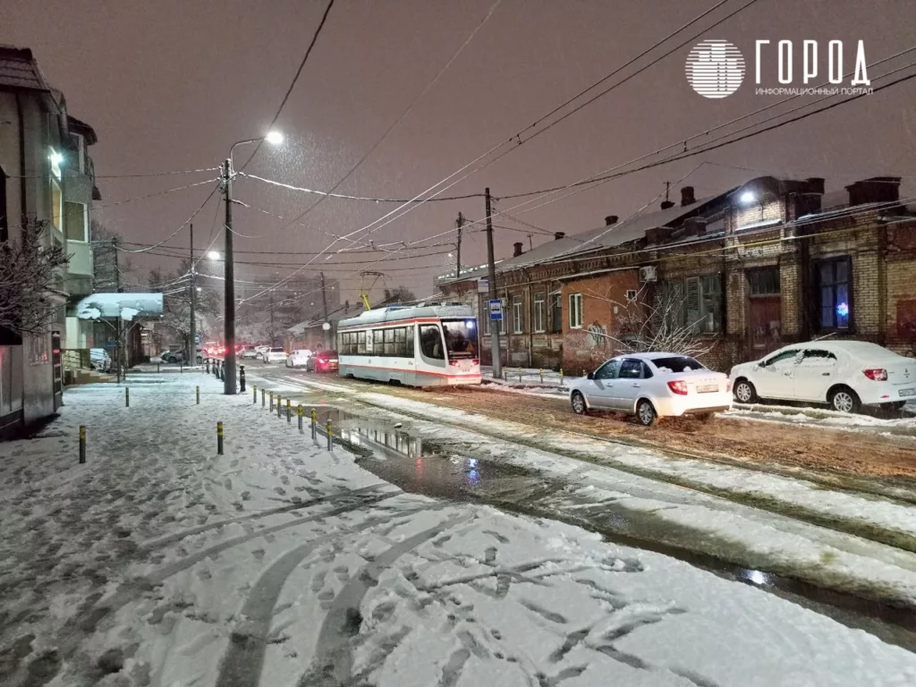 Трамвай в пробке с машинами на улице Кирова во время снегопада в Краснодаре.
